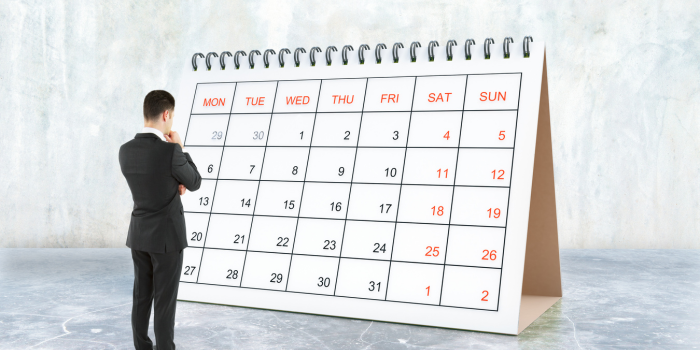 カレンダーの前に立つスーツ姿の男性